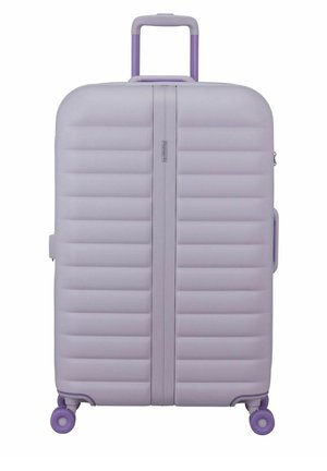 Valise rigide violet clair avec quatre roues, rainures horizontales et une poignée télescopique étendue.