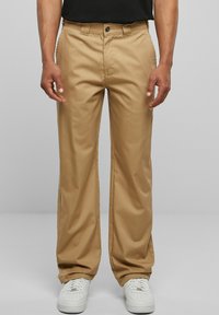 Khaki trousers with a straight-leg design, made from cotton blend fabric, featuring a button closure and belt loops, paired with white sneakers.