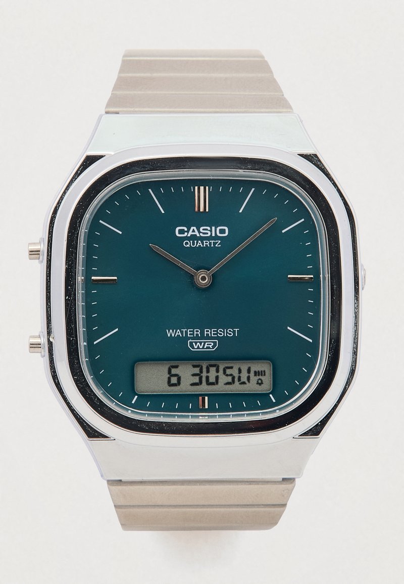 Casio kvarcinis laikrodis su stačiakampiu žaliu ciferblatu, nerūdijančio plieno korpusu ir sidabriniu metaliniu dirželiu. Su skaitmeniniu ekranu ir vandens apsaugos ženklu.