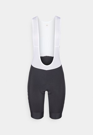 Sorte sykkel-bib-shorts med hvite mesh-stropper, polstret sete og logo nær kanten. Stoffet ser jevnt ut med en strukturert passform.