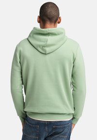 Felpa verde chiaro realizzata in morbido misto cotone, con un ampio cappuccio, polsini a coste e un sottile etichetta con logo vicino all'orlo.