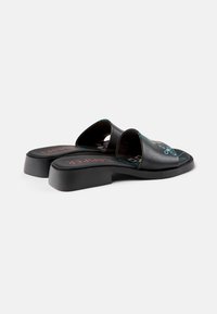 Black leather slide sandals with a wide strap. Features colored floral patterns on the footbed and a low block heel.