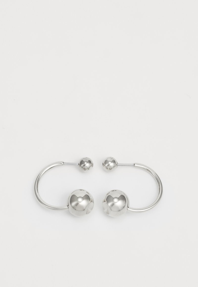 Pendientes de plata que presentan esferas redondeadas y un diseño de alambre curvado. La superficie es lisa con un acabado reflectante.
