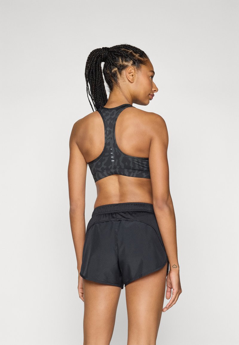Soutien-gorge de sport noir avec un motif léopard subtil et un dos nageur, associé à un short de sport noir ample avec une taille élastique.