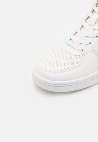 Weiße Leder-Sneaker mit perforierter Zehenbox, flachen Schnürsenkeln und gepolstertem Kragen. Verfügt über eine Gummisohle mit strukturiertem Muster.
