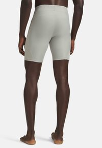 Graue Sportshorts in enger Passform mit einem strukturierten Muster und elastischem Bund. Barfuß getragen, Rückansicht gezeigt.