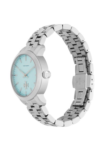 Ceas metalic argintiu cu brățară legată, cadran bleu deschis, marcatoare și ace argintii, având logo-ul Tory Burch la ora 6.