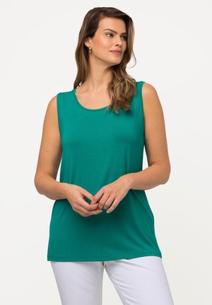Groene mouwloze top van zachte stof, met een ronde halslijn en een relaxte pasvorm, gecombineerd met witte broek.
