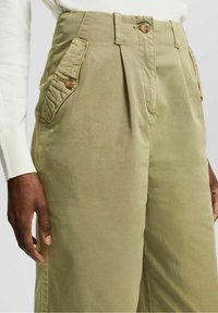 Olive green wide-leg trousers made of cotton, featuring front pleats, two buttoned side pockets, and a smooth texture.