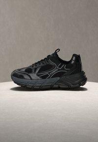 Μαύρο αθλητικό παπούτσι με λεπτομέρειες από πλέγμα και δέρμα, παχύ πάτο και λογότυπο «ICEBERG» στο πλάι, τοποθετημένο σε ουδέτερη επιφάνεια.