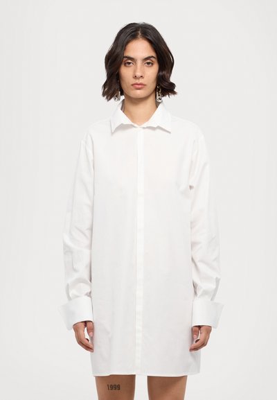 Vit överdimensionerad skjorta, bomullsmaterial, knapprad design, lång ärm med breda manschetter, krage helt knäppt, slät textur.