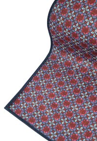 Prostokątny mat tkaninowy z czerwono-niebieskim wzorem kwiatowym, wykończony ciemnoniebieską bordiurą, o teksturowanej powierzchni.