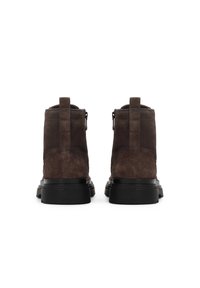 Botas de tobillo de ante marrón con un acabado texturizado, tira en la parte trasera y suela de goma negra. Cuentan con una cremallera lateral para facilitar el uso.