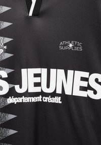 T-shirt de sport noir et gris avec texte blanc « ATHLETIC SUPPLIES », grand « JEUNES » et plus petit « département créatif » sur le devant.