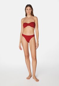 Röd ribbade bikini-set med en strapless-top med en knut fram och lågt sittande trosor. Slät textur med en enfärgad yta.