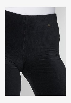 Mustritud mustad corduroy legginsid. Omavad kõrget vööd ja väikest kaubamärgi embleemi esiküljel.