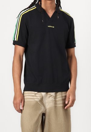 Svart polo t-shirt med V-hals och korta ärmar, med tre ränder i gult, grönt och vitt på axlarna. Adidas-logotyp i grönt.