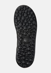 Black rubber shoe sole with textured circular patterns, featuring a rounded shape and "camper" branding near the center.