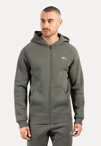 Mørkegrøn zip-up hoodie lavet af blødt materiale med en frontlomme, ribbede manchetter og et broderet logo på venstre bryst.
