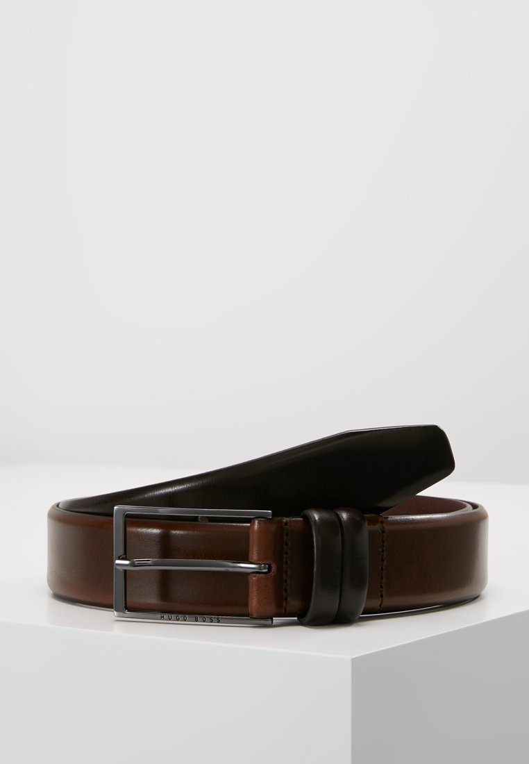 Ceinture en cuir marron, présentant une boucle noire brillante, un design bicolore et une texture lisse, avec un accent en métal argenté.