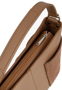 Borsa a tracolla in pelle marrone con una tasca in morbido camoscio, chiusura con zip e tracolla regolabile. Presenta cuciture ordinate e un design strutturato.