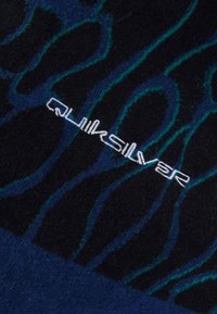 Melna auduma ar ziliem viļņveida rakstiem; izceļas ar baltu "Quiksilver" logotipu. Tekstūra izskatās mīksta un adīta.