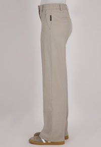 Beige, rechte broek van een gladde stof, met een achterzak, een elastische tailleband en een subtiele logotag. Past goed bij comfortabele schoenen.