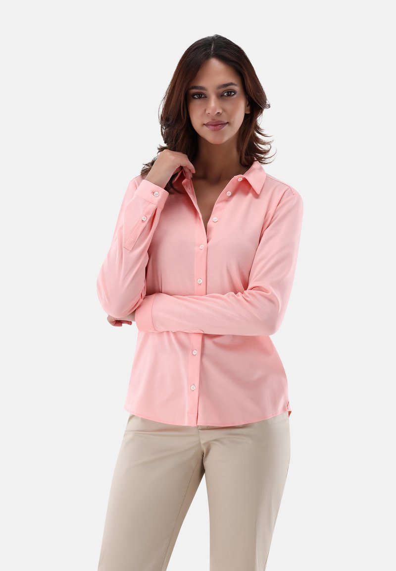 Light coral long-sleeve button-up shirt with a collar, featuring a smooth texture and fitted design, paired with light beige trousers.