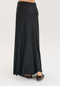 Čierna maxi sukňa z hladkého, ľahkého materiálu, s elastickým pásom, dĺžkou až k podlahe a miernym rozšírením na leme.