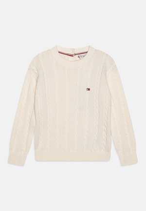Pull en maille torsadée de couleur crème avec manches longues et petit logo rectangulaire rouge, blanc et bleu sur la poitrine.