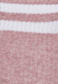 Nahaufnahme eines rosa Strickstoffs mit zwei horizontalen weißen Streifen, die die feine gerippte Textur und das Nähmuster zeigen.