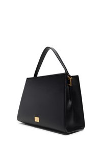Sac �à main en cuir noir avec une forme structurée, un fond plat, une seule poignée supérieure, une plaque logo dorée et une finition texturée.