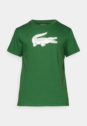 Grünes Baumwoll-T-Shirt mit einem großen weißen Krokodil-Print auf der Vorderseite. Rundhalsausschnitt mit kurzen Ärmeln und einer glatten Textur.