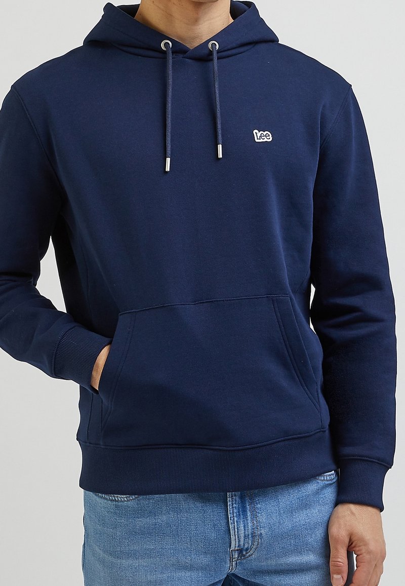 Felpa con cappuccio blu navy realizzata in tessuto morbido, dotata di tasca frontale a marsupio, occhielli in tono argento e un piccolo logo sul petto.