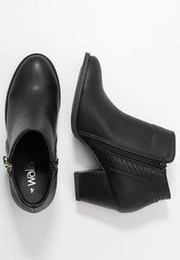 Botas negras hasta el tobillo con parte superior de cuero suave, panel lateral texturizado y tacón cuadrado. Cuenta con cierre de cremallera y diseño de punta redonda.