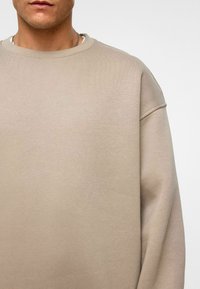 Beige sweatshirt met een ribbeltextuur, ronde hals en verlaagde schouders. Eenvoudig en casual ontwerp, geschikt voor ontspannen draagmomenten.