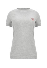 T-shirt gris clair à manches courtes avec un petit logo Guess rouge et blanc sur le haut gauche de la poitrine et un texte à l’intérieur du col.