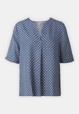 Sinine lühikese käisega pluus V-kaelusega, millel on geomeetriline valge ja punane muster. Valmistatud kergest kangast, millel on mugav lõige.