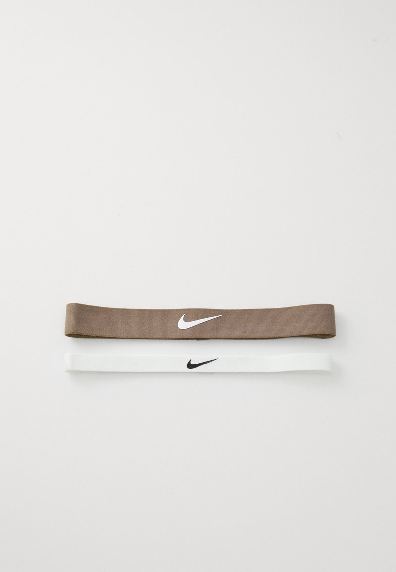 Dvije elastične trake za kosu: jedna smeđa s bijelim Nike logotipom, a druga bijela s crnim Nike logotipom, obje ravne i glatke teksture.
