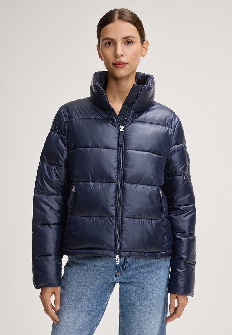 Giubbotto invernale blu navy con colletto alto, chiusura con zip e pannelli imbottiti orizzontali. Presenta tasche laterali e una finitura lucida e elegante.