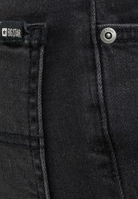 Černá džínová látka s viditelnými švy kapes, kovovým nýtem s nápisem "BIG STAR" a černou textilní štítkem s nápisem "BIG STAR" a hvězdným logem.