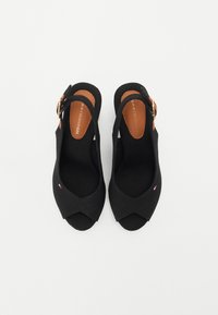 Tacchi a sfilo neri con design open toe, dotati di upper in tessuto, soletta beige e hardware con fibbia dorata. Presenza di un piccolo dettaglio con logo.