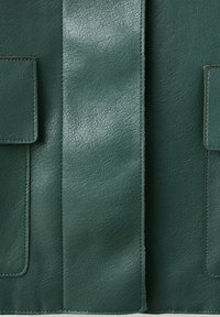 Material din piele verde închis cu textură granuloasă vizibilă, prevăzut cu două buzunare dreptunghiulare și un panou vertical central cu cusături.