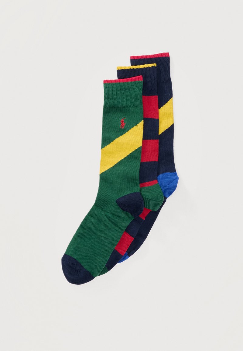 Τρία ζευγάρια κάλτσες μήκους μέχρι τη μέση της γάμπας σε πράσινο με κίτρινη διαγώνια ρίγα, κόκκινο με ριγέ σε ναυτικό μπλε και ναυτικό μπλε με κίτρινη διαγώνια ρίγα.