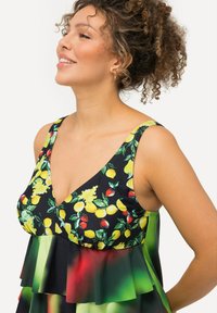 Klänning med blommönster som har citron- och bärdesign på en svart bakgrund. Inkluderar en volangnederkant och livfulla gröna detaljer.