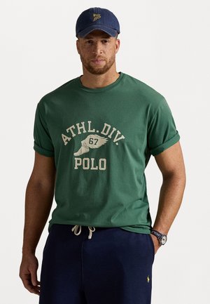 Zelené bavlnené tričko s prehnutými rukávmi, s krémovým grafickým potlačou s nápisom "ATHL.DIV. POLO" a námorníckou čiapkou s logom.