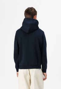 Marinblå hoodies, mjukt tyg, avslappnad passform, ribbade ärmslut och nederkant, stor huva, minimalistisk design utan synliga logotyper.