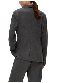 Blazer gris ajusté avec une texture lisse, une fente au dos et un design de col élégant. Associé à un pantalon gris assorti.