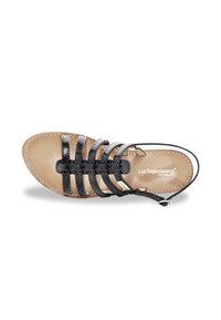 Sandal de tiras negras con múltiples tiras trenzadas, suela plana y una plantilla de color marrón claro ligeramente acolchada. Presenta un diseño minimalista y correa de talón ajustable.