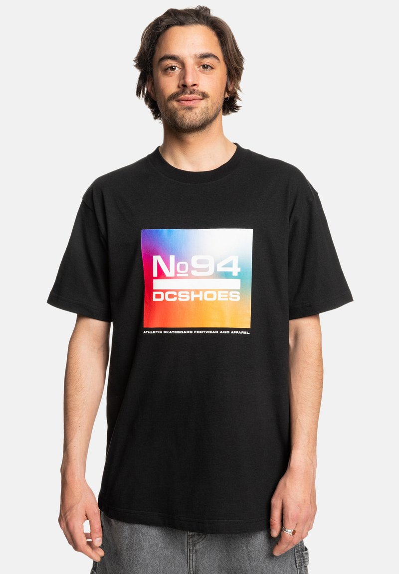 Zwarte katoenen t-shirt met een grote gradient graphic en het logo "No 94" en "DCSHOES" in het wit. Korte mouwen, relaxte pasvorm, minimale structuur.